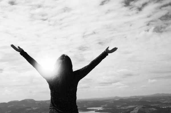 woman looking to the sky with arms raised high praising God